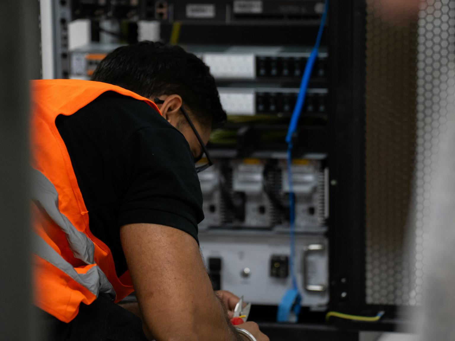 A technician working on equipment at an open server rack